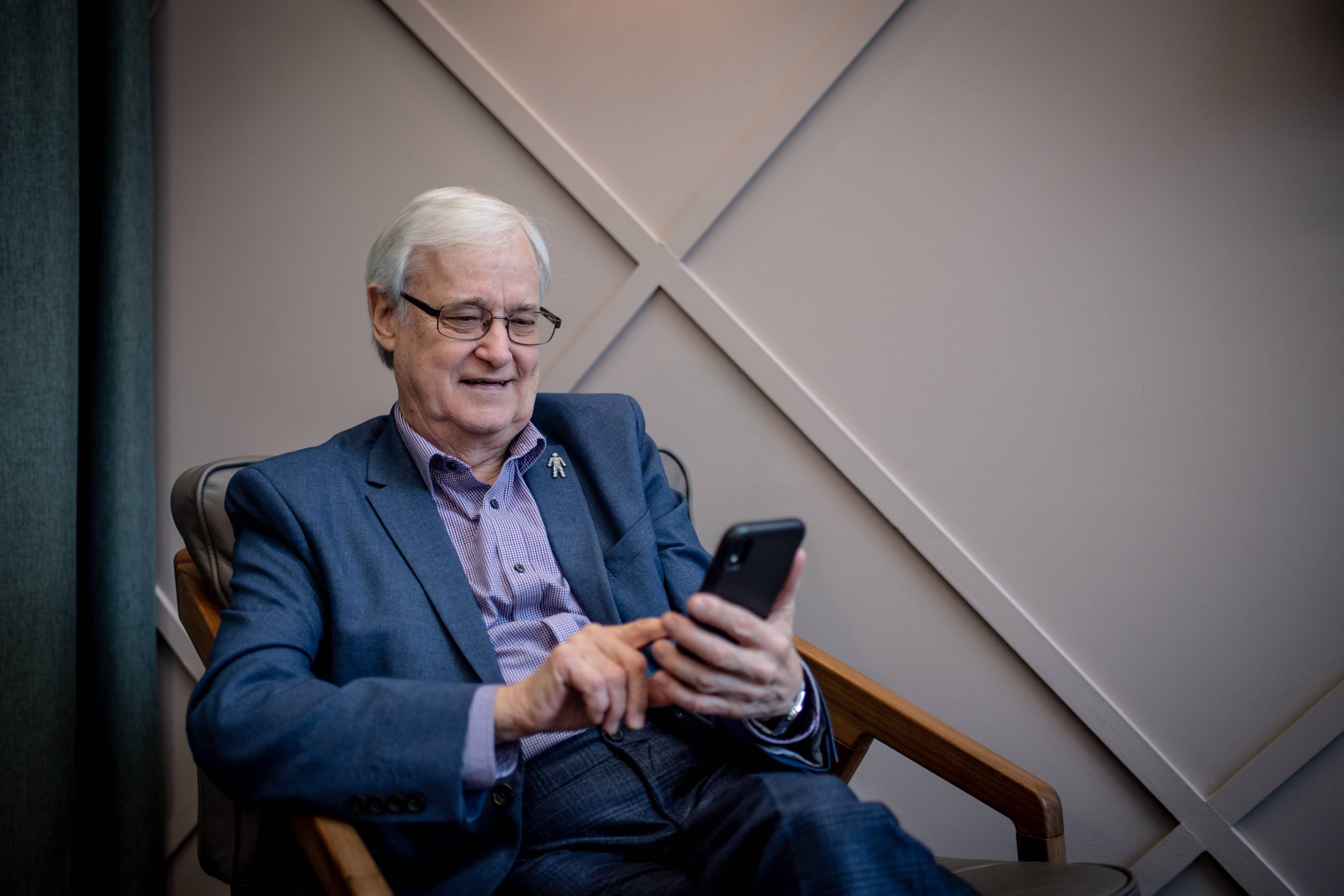 Older man with prostate cancer badge on a smartphone