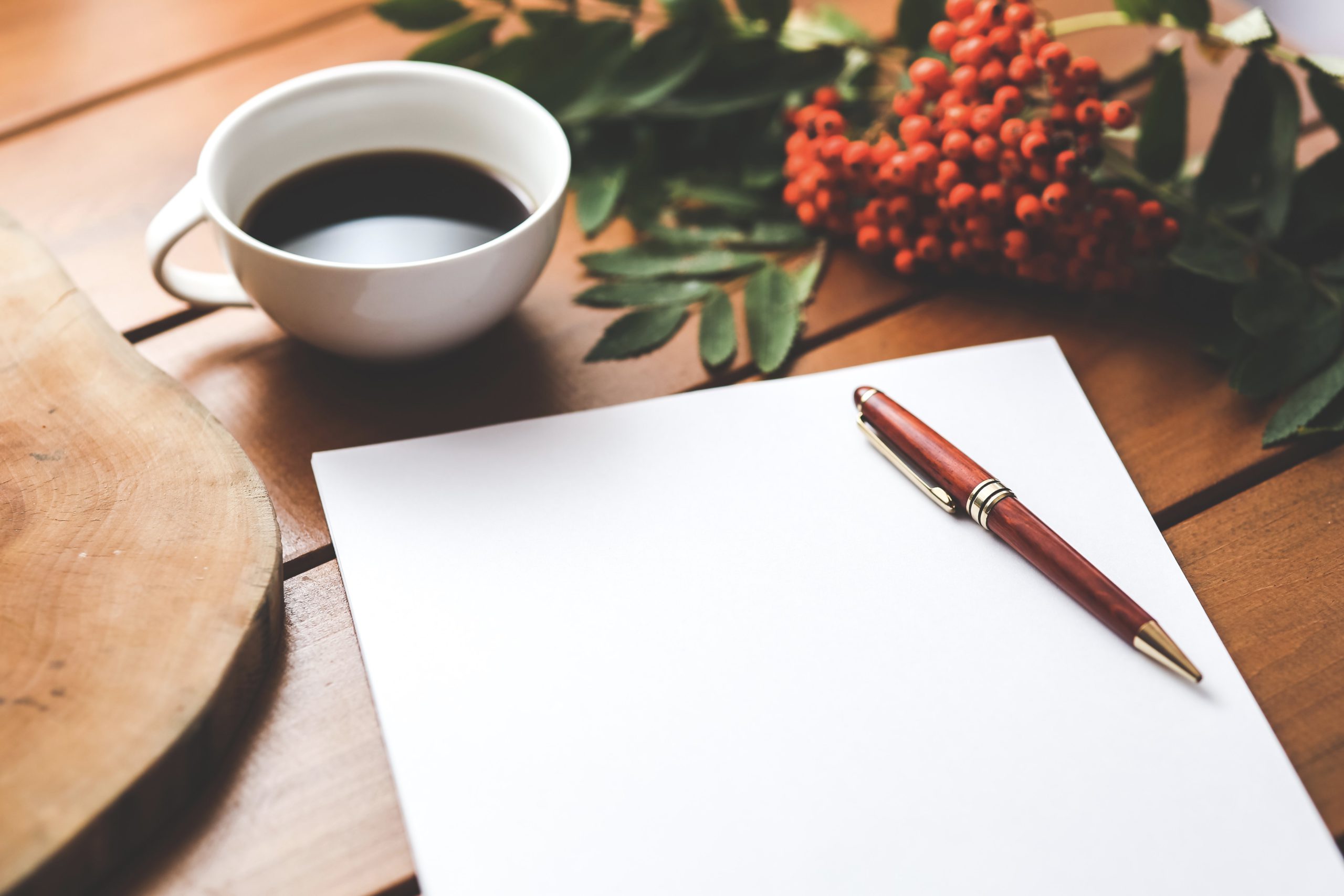 Writing pad with pen and coffee on table